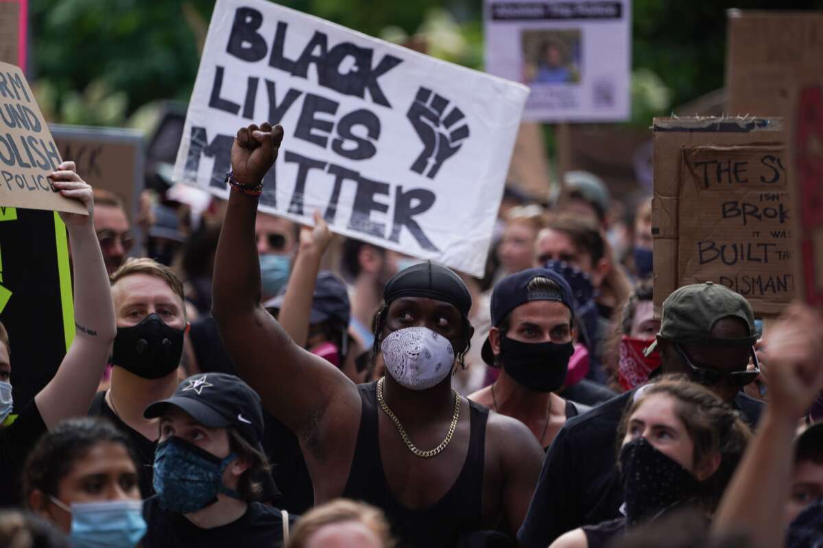 Protesters hold a "Black Lives Matter" sign and raise their fists as they march through Greenwich Village in New York City on June 19, 2020, in a demonstration over the death of George Floyd by Minneapolis Police.