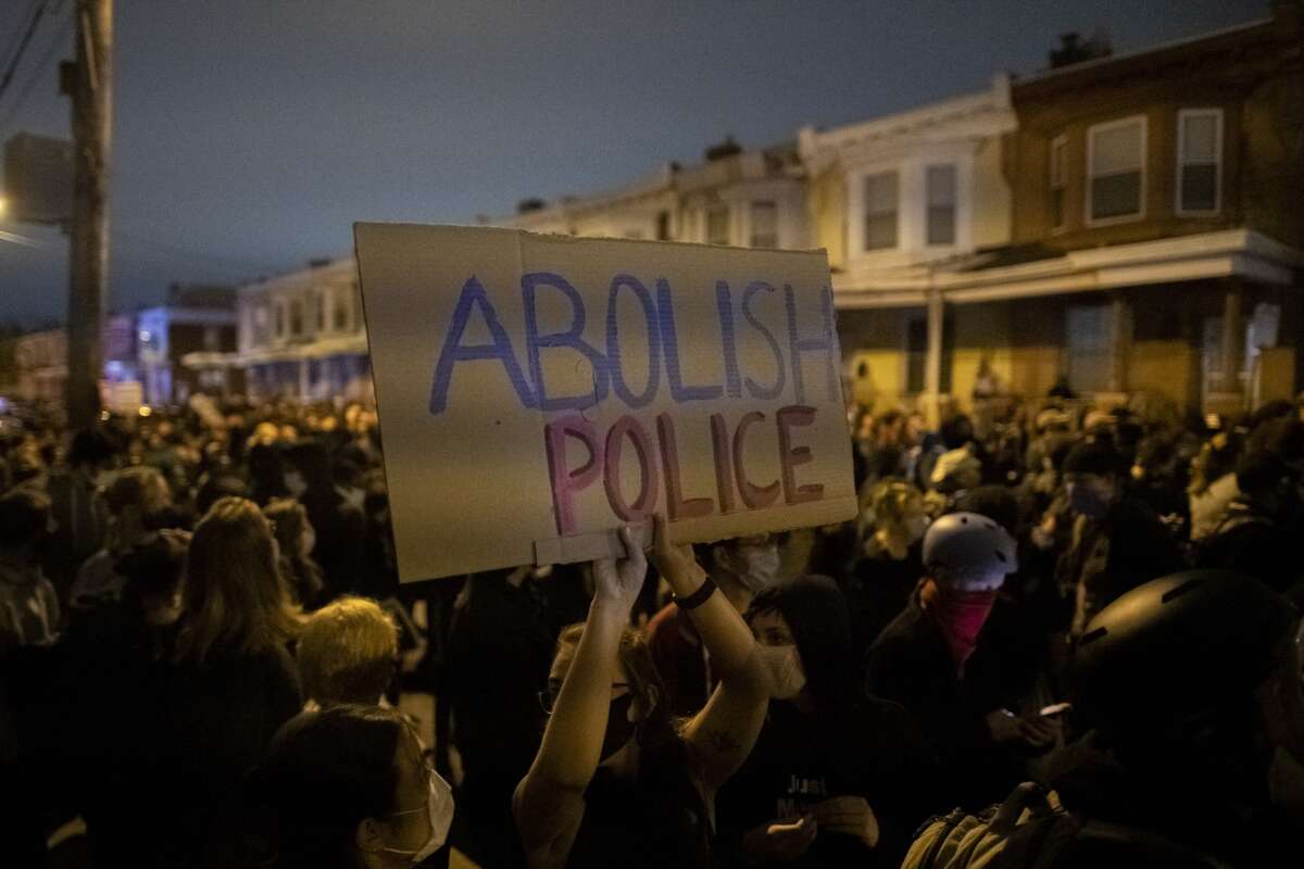 A demonstrator holds a placard reading "ABOLISH POLICE" during a protest on October 27, 2020, near the location where Walter Wallace Jr. was killed by two police officers in Philadelphia, Pennsylvania.