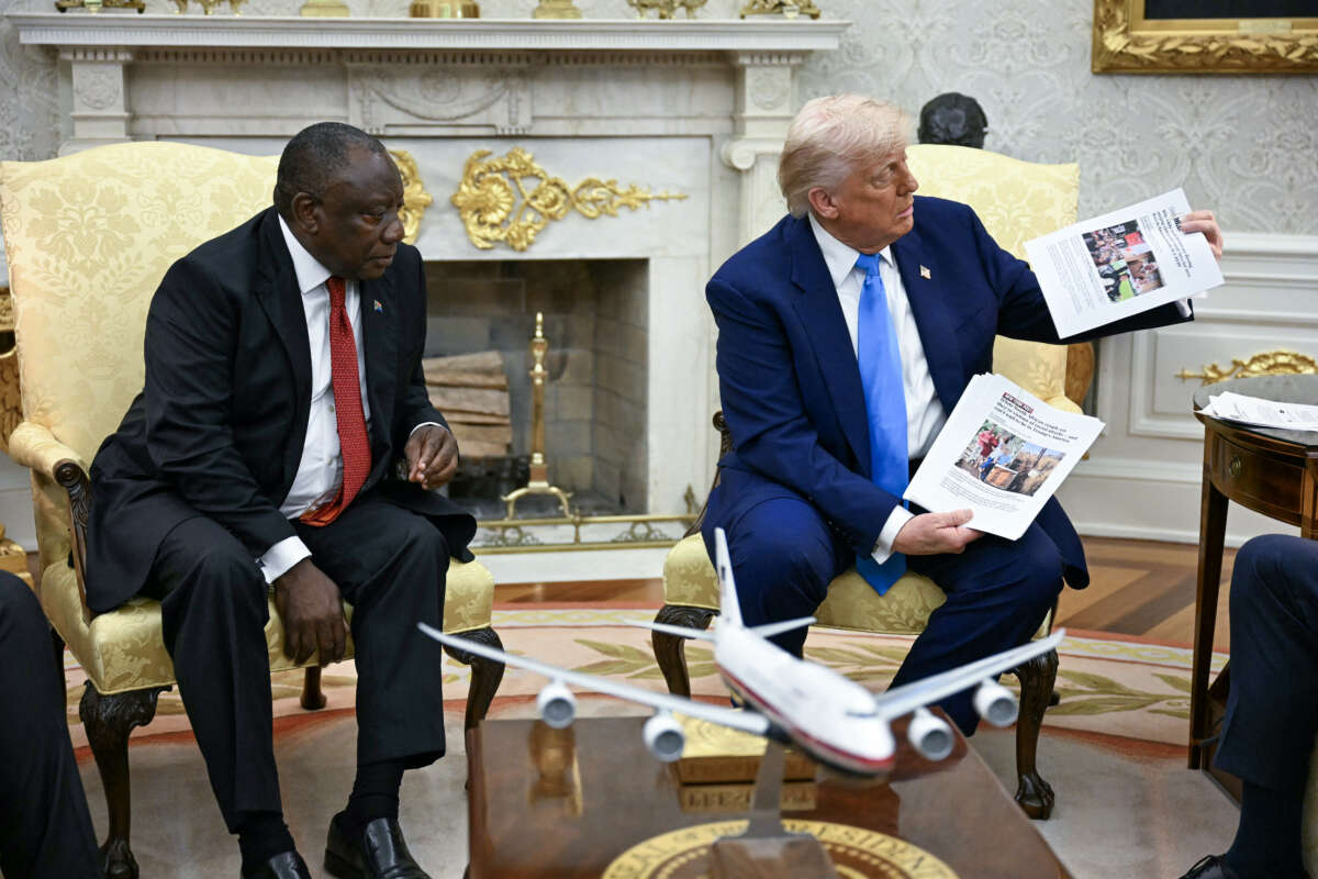 U.S. President Donald Trump shows pictures as he meets with South African President Cyril Ramaphosa in the Oval Office of the White House in Washington, D.C., on May 21, 2025. Ramaphosa meets Donald Trump amid tensions over Washington's resettlement of white Afrikaners that the U.S. president claims are the victims of "genocide."