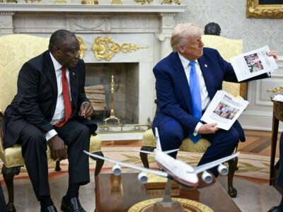 U.S. President Donald Trump shows pictures as he meets with South African President Cyril Ramaphosa in the Oval Office of the White House in Washington, D.C., on May 21, 2025. Ramaphosa meets Donald Trump amid tensions over Washington's resettlement of white Afrikaners that the U.S. president claims are the victims of "genocide."