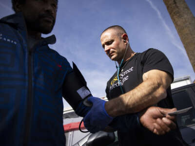 Charles Wilkerson III, 43, left, gets his blood pressure taken by USC Director of Street Medicine Brett Feldman, right, at the intersection of James M. Wood Boulevard and Beacon Avenue on Monday, February 23, 2026 in Los Angeles, California. Brett Feldman and the USC Street Medicine team provide medical care to the unhoused community in Los Angeles.