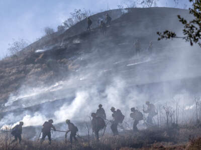 Orange County Fire Authority firefighters work to extinguish flames and embers on a dry, grassy hillside at Narrow Canyon Road and Acaster Way in Ladera Ranch, California, as they battle the Narrow fire on July 7, 2026.