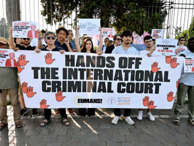 People take part in a demonstration in defense of the International Criminal Court, holding banners reading "Hands off the International Criminal Court" and placards depicting Donald Trump, Vladimir Putin, and Ursula von der Leyen, at Piazza Ugo La Malfa, on July 16, 2026 in Rome, Italy.
