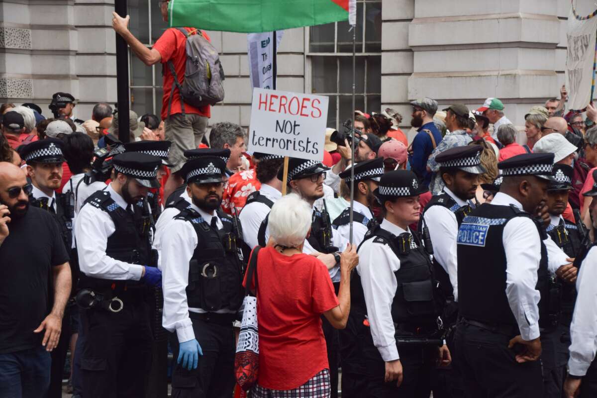 A protester holds a 'Heroes not terrorists' placard as police officers get ready to make arrests during a demonstration outside Westminster Magistrates Court organized by Defend Our Juries against the ban on the activist group Palestine Action.