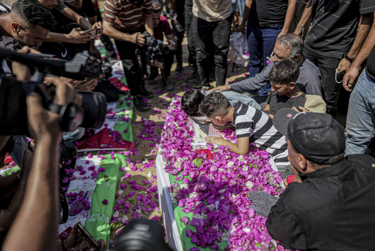 Mourners gather around a flower-covered coffin during a funeral procession in Gaza City, Gaza Strip, on August 4, 2026. The remains of 112 members of the Abu Sharia and Al-Hasayneh families were recovered from the rubble of their home following an Israeli strike. Relatives stated the attack claimed the lives of more than 300 people.