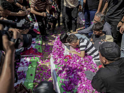 Mourners gather around a flower-covered coffin during a funeral procession in Gaza City, Gaza Strip, on August 4, 2026. The remains of 112 members of the Abu Sharia and Al-Hasayneh families were recovered from the rubble of their home following an Israeli strike. Relatives stated the attack claimed the lives of more than 300 people.