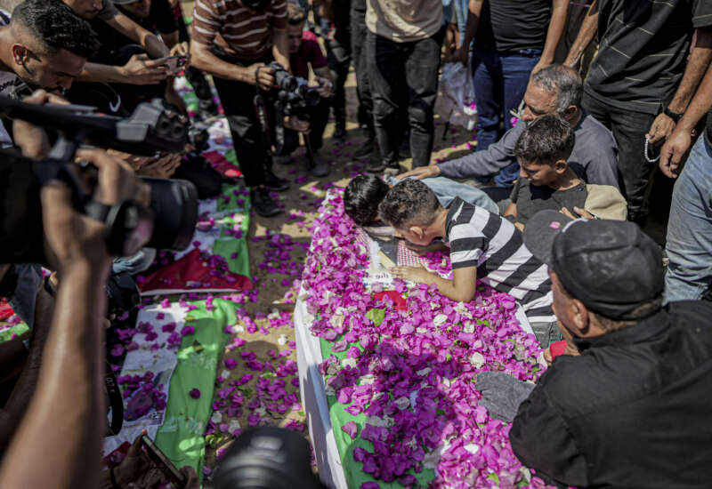 Mourners gather around a flower-covered coffin during a funeral procession in Gaza City, Gaza Strip, on August 4, 2026. The remains of 112 members of the Abu Sharia and Al-Hasayneh families were recovered from the rubble of their home following an Israeli strike. Relatives stated the attack claimed the lives of more than 300 people.