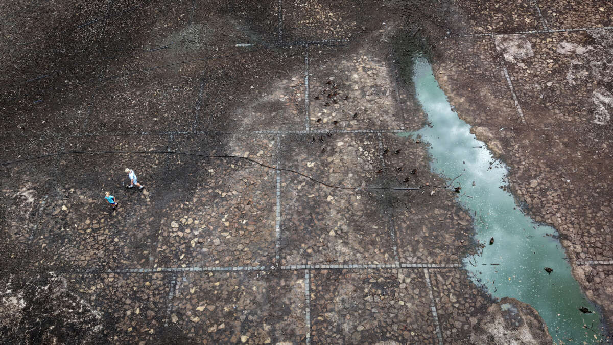 In this aerial view children walk on the bed of Heath Park Lake which has dried up due to the current water shortage and lack of maintenance, local residents claim, on August 19, 2026, in Runcorn, United Kingdom.