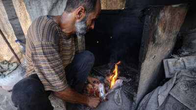 Mohammed al-Tarabish, a father of five, displaced from his home in Beit Hanoun in the norther Gaza Strip and currently living in a tent in Bureij, in the central Gaza Strip, lights combustible material collected from a garbage dump to be used as fuel for cooking due to a shortage of cooking gas, on August 24, 2026.