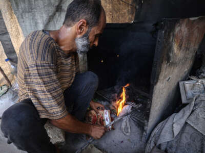 Mohammed al-Tarabish, a father of five, displaced from his home in Beit Hanoun in the norther Gaza Strip and currently living in a tent in Bureij, in the central Gaza Strip, lights combustible material collected from a garbage dump to be used as fuel for cooking due to a shortage of cooking gas, on August 24, 2026.