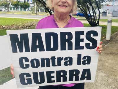 Sonia Santiago Hernandez holds a sign reading “Madres Contra la Guerra” by the international airport in San Juan, Puerto Rico.