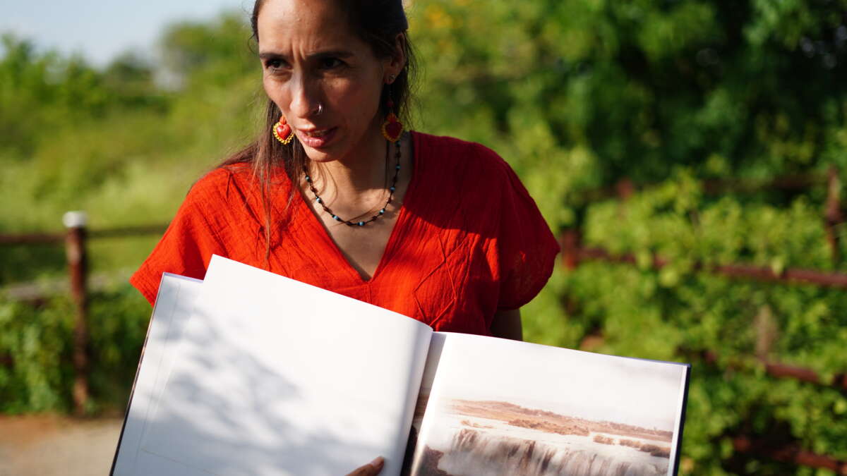 Atahualpa Sofía Enciso lives near the Santiago River and is a member of Salto de Vida, a collective that defends it. She holds a book showing what the river used to look like.
