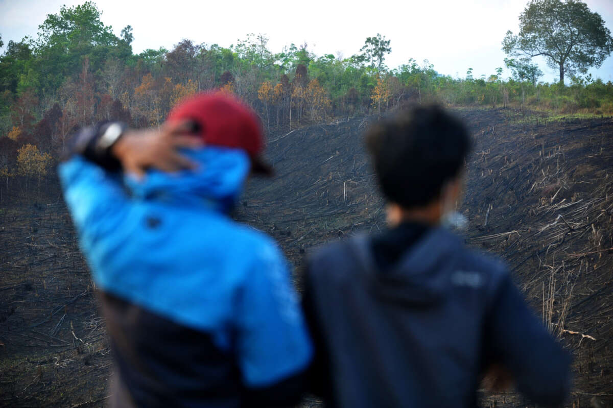 Residents look on at burned forested land, thought to be caused by large-scale land-clearing for fields that damage the ecosystem, in West Kalimantan, Indonesia, on September 19, 2018.