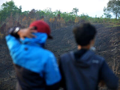 Residents look on at burned forested land, thought to be caused by large-scale land-clearing for fields that damage the ecosystem, in West Kalimantan, Indonesia, on September 19, 2018.