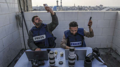 Palestinian journalists attempt to connect to the internet using their phones in Rafah on the southern Gaza Strip on December 27, 2023.
