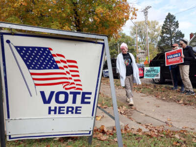 Volunteers hold signs outside a polling location as a woman walks in to vote on November 5, 2024, in Kansas City, Missouri.