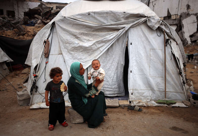 A Palestinian mother plays with her child as she sits in front of her tent in a displacement camp in Gaza City, on May 12, 2025.