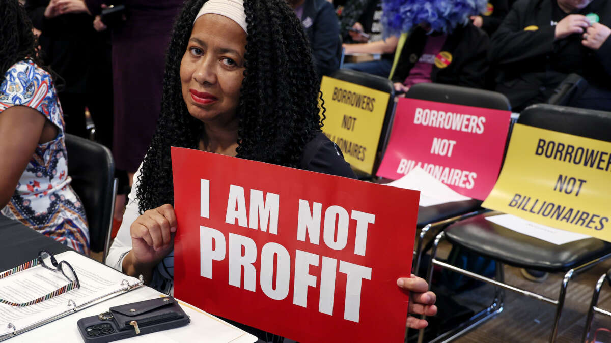 Veteran and student loan borrower Bonni Snider holds up a "I Am Not Profit" sign prior to a special forum on the rising cost of education at the Dirksen Senate Office Building on May 14, 2025, in Washington, D.C.