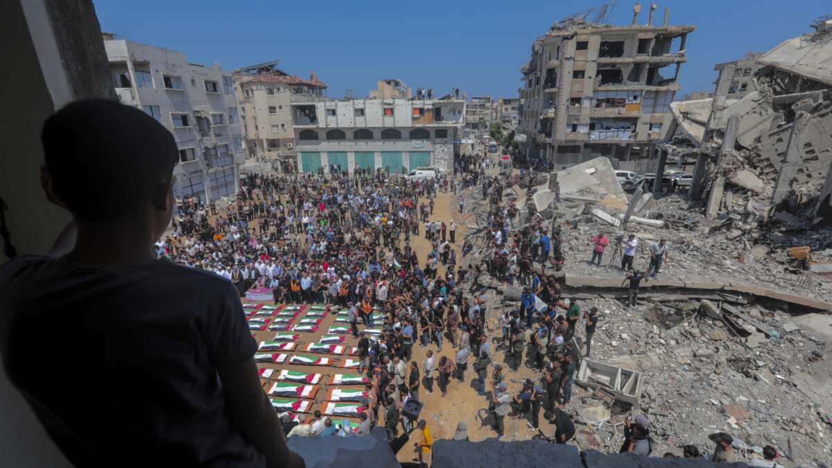 Mourners gather around rows of bodies wrapped in Palestinian flags during a mass funeral procession in the Al-Sabra neighborhood of Gaza City, Gaza Strip, on August 4, 2026.