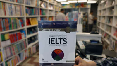 A bookstore employee displays an International English Language Testing System (IELTS) book in Tehran, Iran, on September 7, 2026. Testing has been suspended in Iran since September 1 following the latest U.S. sanctions.