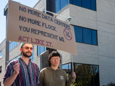 Demonstrators hold a protest sign reading ''No More Data Centers. No More Flock. You Represent Us. Act Like It.'' during a community rally opposing a proposed data center zoning ordinance outside the Utah County Administration Building in Provo, Utah, on October 7, 2026.