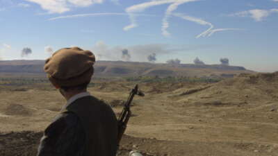 From the summit of Ai Khanoum, a former citadel of Alexander the Great, a Northern Alliance soldier passively watches U.S. air strikes over Taliban lines, on November 4, 2001.