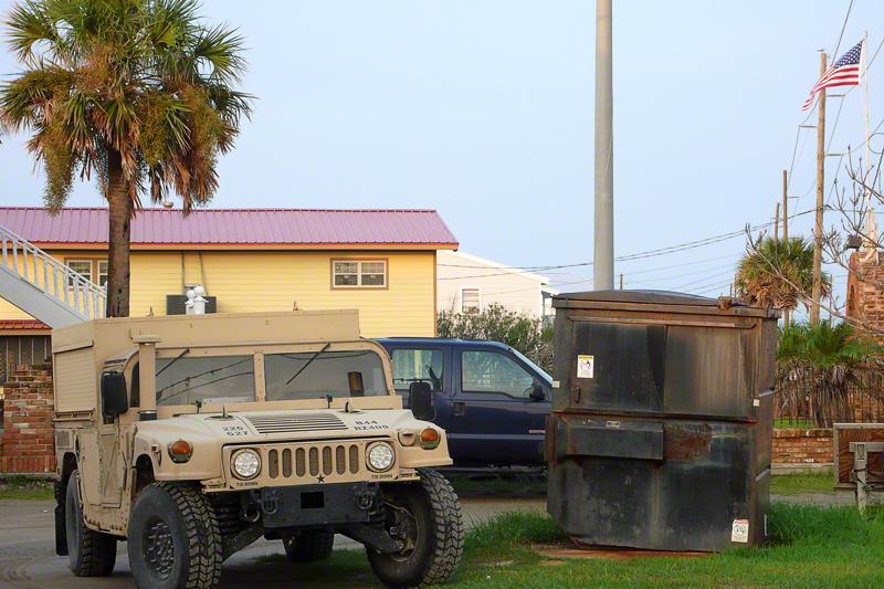 Two military Humvees, one olive green, the other tan, are parked near the road just yards from our car.