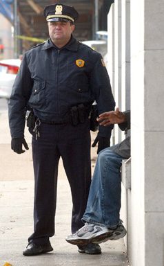 Lt Felix Calvi of the Memphis Police Department stands next to Robert Warren, a homeless man. They are waiting for a local shelter to come and pick Warren up during the first day of a city-wide sweep of the homeless population ordered by the Mayor's office. Photo: John Mottern