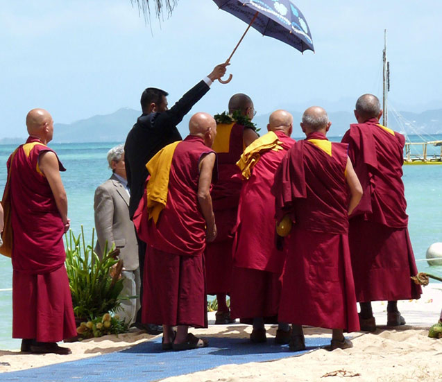 A group of five Tibetan Buddhist monks watch as the Dalai Lama blesses the Hawaiian voyaging canoe Hokulea on the final day of his four-day stay, part of a new initiative called Pillars of Peace Hawaii. (Photo: Jon Letman)