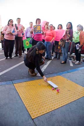 Robledo puts her letter and carnations on the pavement in front of the doors. (Photo: David Bacon)