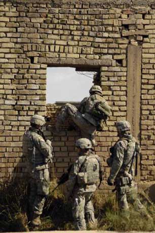 U.S. Army Soldiers climb through a wall to get to the next objective during an operation in Zaghiniyat, Iraq, March 29, 2007.