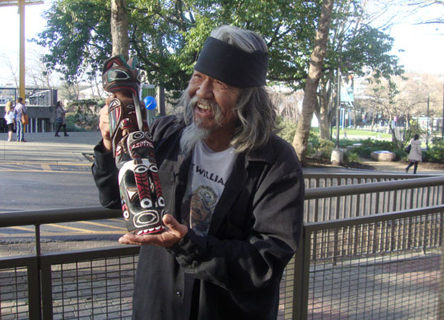 Rick Williams holding a totem pole he hand-carved and painted. Photo by Kayla Schultz.