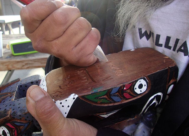 Rick Williams carving his name into a totem pole a customer purchased. Photo by Kayla Schultz.