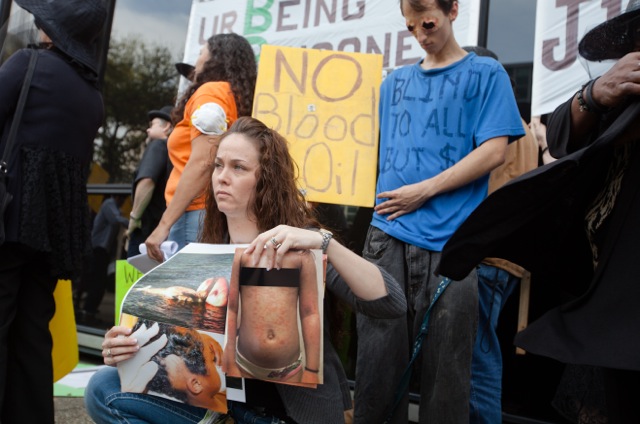 Kindra Arnesen holds up photographs of people and animals sickened since the BP oil spill during a protest in New Orleans on Feb. 29, 2012. (Julie Dermansky)