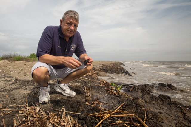 Dean Blanchard picks up a piece of tar from a tar mat on East Grand Terre Island in Barataria Bay on April 9, 2015. (Photo: Julie Dermansky)