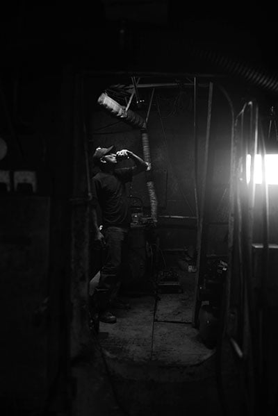 The deckhand of a shrimping vessel drinks a beer after installing the ship's new ice machine. (Photo: Michael Stein)