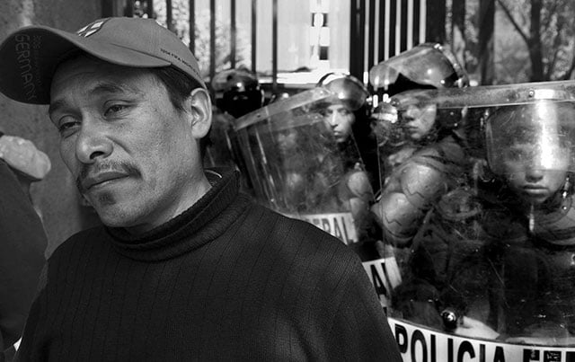 A striking teacher from Michoacán demonstrates in Mexico City in front of a line of police. Canadian and US teachers have organized the TriNational Coalition to Defend Public Education to support Mexican teachers’ efforts to defeat proposals to introduce standardized testing and remove job protections, which have come from USAID and private foundations promoting corporate education reform. (Photo: David Bacon)