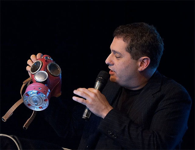 Bogad explaining the bejazzled gas mask, a key costume piece for creative protest, at a keynote talk in Helsinki, 2012.