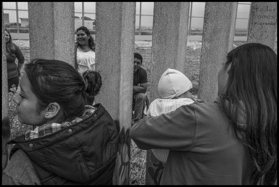 Adriana Arzola, her sister and her baby, Nayeli Santana, talk with her family living in the US through the bars of the wall. On the US side, her family has to stay several feet away from the wall, so they can't touch each other through the bars. (Photo: David Bacon)