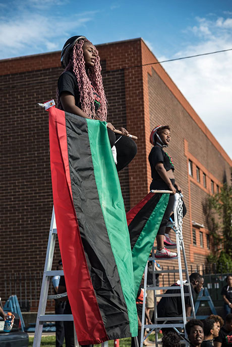 Two protesters sat atop ladders, chained in place as BYP 100 and the #LetUsBreathe collective formed a blockade at Chicago's infamous Homan Square facility. (Photo: Sarah-Ji)