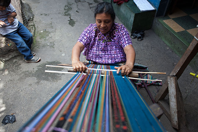 Another member of the 13 B'atz' weavers collective sits on the floor of the house as she weaves. (Photo: Jeff Abbott)