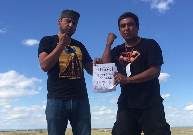Native protesters Dean Dedman and Remy show their support for #FreedomSquare from the frontlines of #NoDAPL. Dedman has played a key role in documenting the #NoDAPL protests, while Remy, an arts trainer with The Indian Problem, has helped produce art on the frontlines. (Photo: Desiree Kane)
