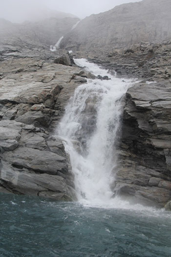 One of many waterfalls cascades down the vertical cliffs of Sam Ford Fiord, testament to the volume of glacier melt. (Photo: Chris Williams)