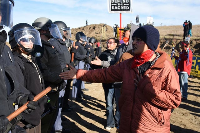 Members of the Indigenous Youth Council extend their hands to an unmoving line of police officers during the demonstration against the Dakota Access pipeline in Standing Rock on October 10, 2016. (Photo: Ellen Davidson)