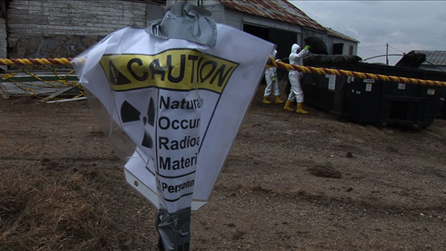 A caution sign is taped to a fence post outside an abandoned gas station in Noonan, ND where radioactive oil field socks were found. (Photo: David Geck)