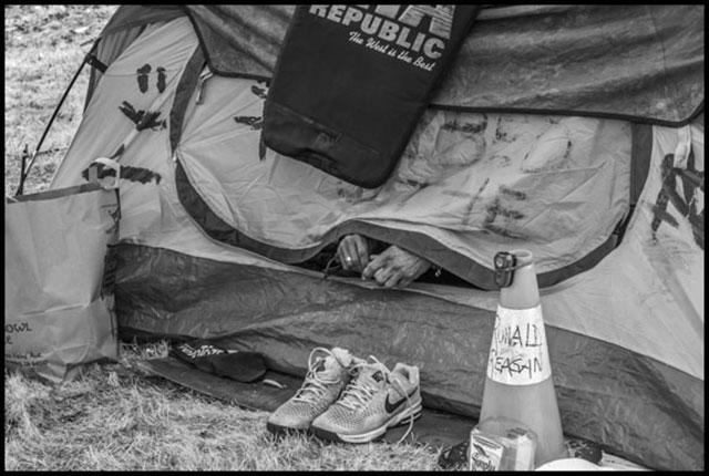 Ronald Vargas sticks his hands out of the tent in the morning, looking for his shoes. (Photo: David Bacon)