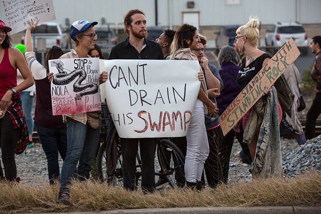 Chris Saudinger, a writer from New Orleans, holding a protest sign 