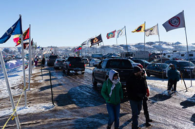 Right, the entrance to the Oceti Sakowin camp is lined with flags from visiting tribes. (Photo: Joseph Zumo)
