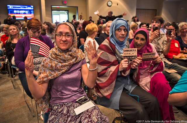 Though signs were forbidden in the town hall meetings, some snuck some in under the radar. (Photo: Julie Dermansky)