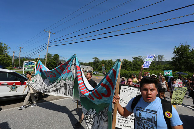 Enrique “Kiké” Balcazar leading farmworkers and allies past police, towards the Ben & Jerry’s factory. (Photo: Jonathan Leavitt)